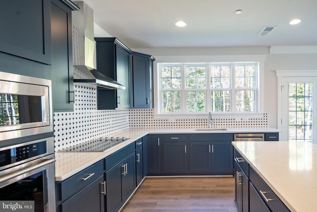 kitchen featuring stainless steel appliances, dark hardwood / wood-style flooring, decorative backsplash, sink, and wall chimney exhaust hood