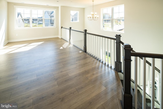 stairway featuring an inviting chandelier and wood-type flooring