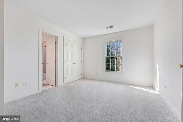 unfurnished bedroom featuring light carpet and ensuite bathroom