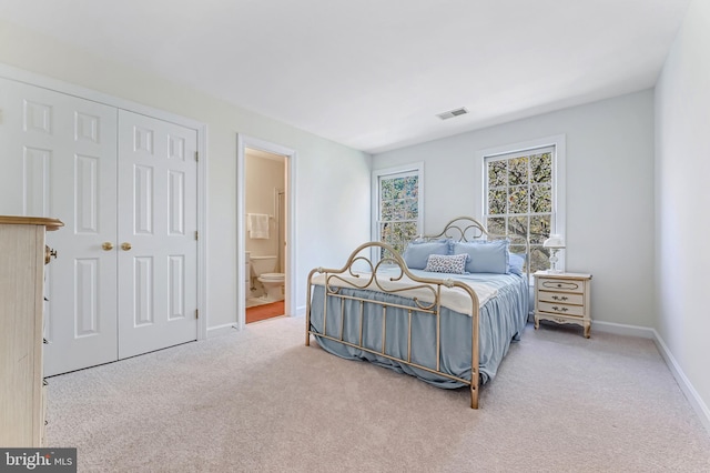 bedroom featuring light colored carpet, ensuite bath, and a closet