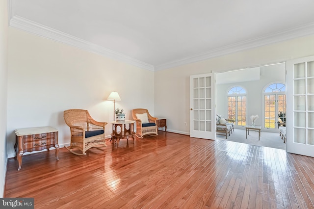 sitting room featuring french doors, ornamental molding, and hardwood / wood-style flooring