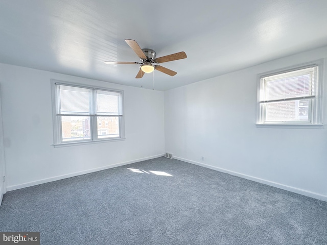 unfurnished room with ceiling fan and dark carpet