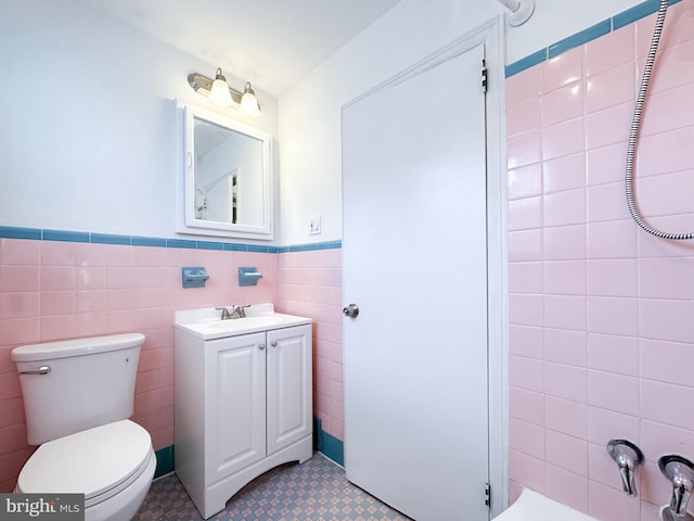 bathroom featuring vanity, tile walls, and toilet