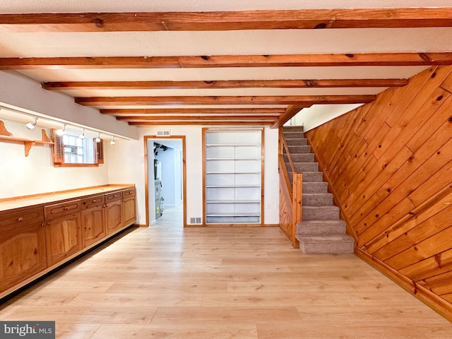 interior space featuring light hardwood / wood-style floors, beam ceiling, and wooden walls