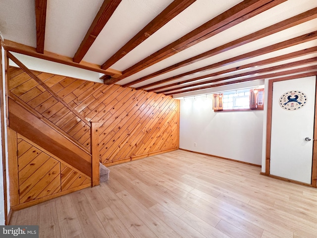 basement featuring light wood-type flooring and wooden walls