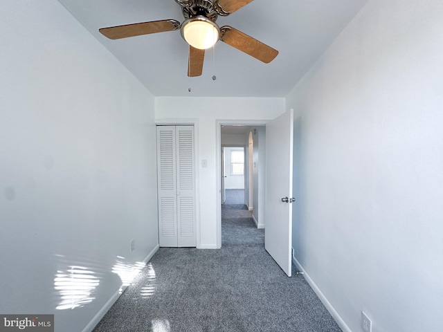 unfurnished bedroom with ceiling fan, dark carpet, and a closet