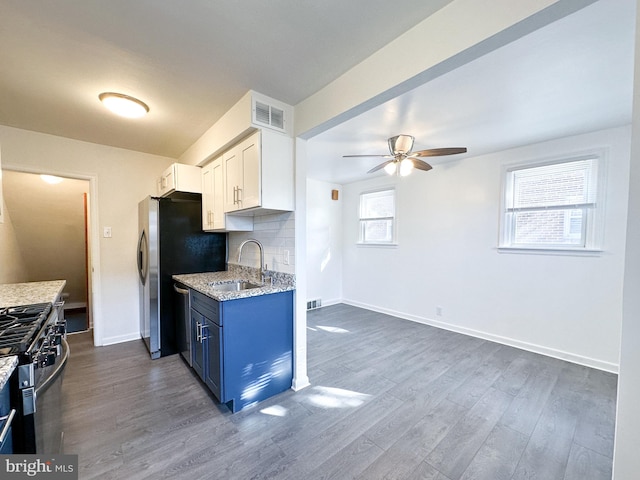 kitchen featuring dark wood-type flooring, white cabinets, blue cabinets, sink, and light stone counters