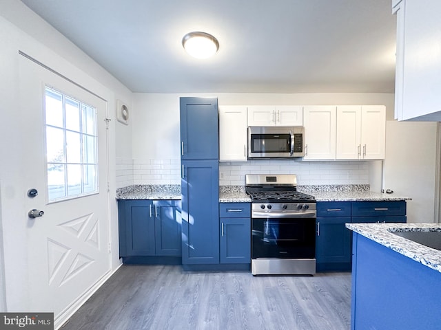 kitchen featuring white cabinets, stainless steel appliances, light stone countertops, and light hardwood / wood-style floors