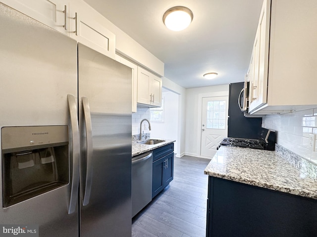 kitchen with tasteful backsplash, sink, white cabinets, and stainless steel appliances