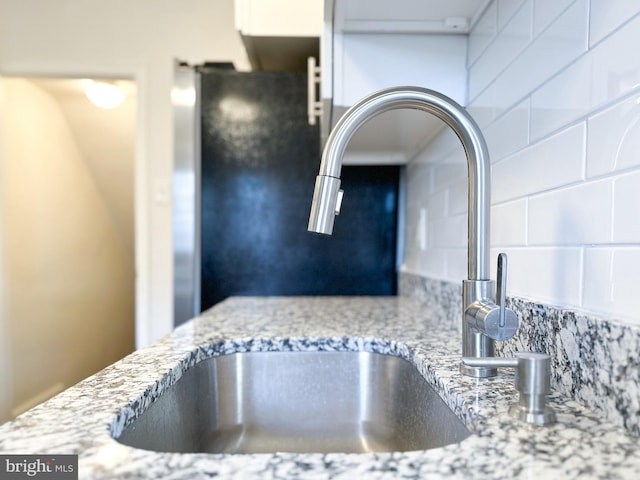 interior details with decorative backsplash, light stone counters, and sink