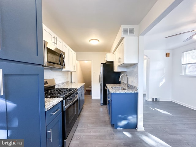 kitchen with dark hardwood / wood-style flooring, tasteful backsplash, stainless steel appliances, sink, and white cabinets