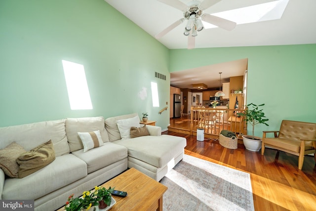 living room with high vaulted ceiling, wood-type flooring, ceiling fan, and a skylight