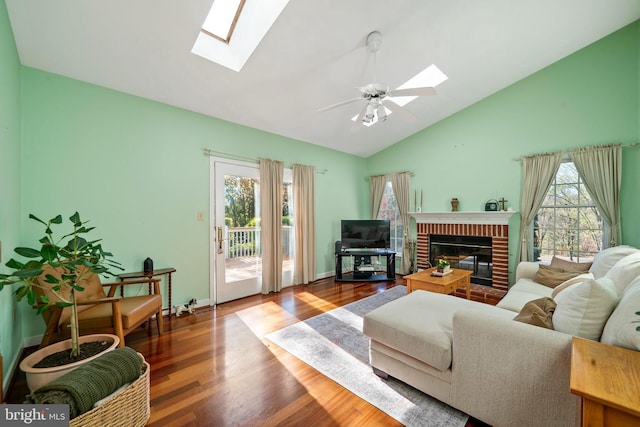 living room featuring hardwood / wood-style floors, plenty of natural light, lofted ceiling with skylight, and a brick fireplace