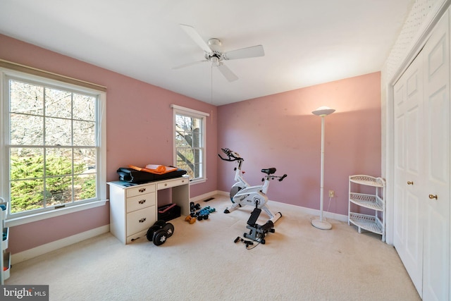 exercise area featuring light colored carpet, a healthy amount of sunlight, and ceiling fan