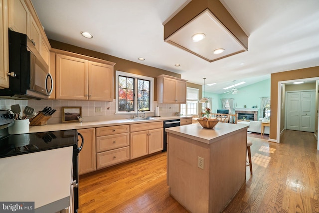 kitchen with light hardwood / wood-style floors, decorative light fixtures, white range, a kitchen island, and a brick fireplace