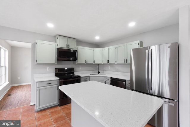 kitchen featuring sink, light tile patterned floors, a kitchen island, light stone countertops, and black appliances