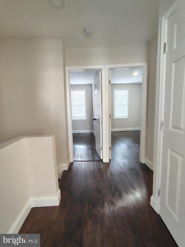 hall featuring dark wood-type flooring and baseboards