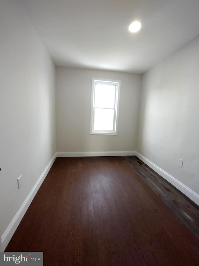 unfurnished room featuring dark wood-type flooring and baseboards