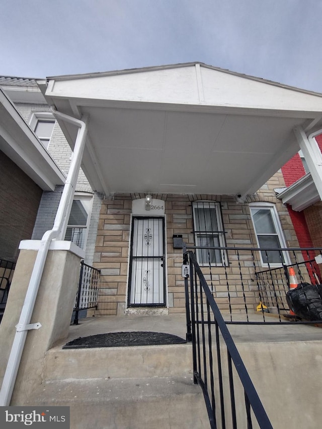 entrance to property with a porch, brick siding, and stone siding