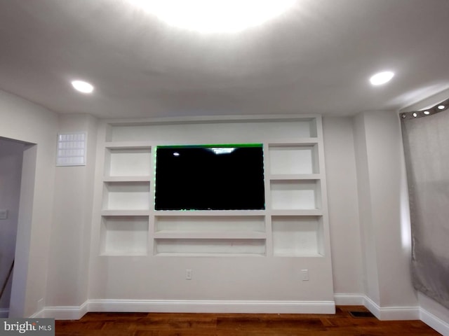 unfurnished living room with recessed lighting, baseboards, built in shelves, and dark wood finished floors