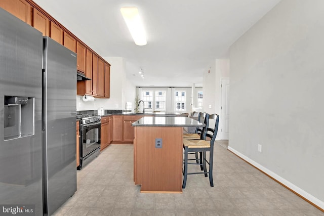 kitchen with a kitchen bar, stainless steel refrigerator with ice dispenser, black range with gas stovetop, sink, and a kitchen island