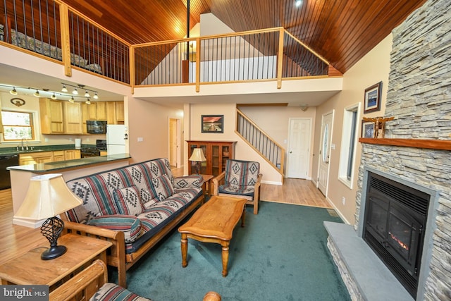 living room featuring a fireplace, sink, high vaulted ceiling, and wood ceiling