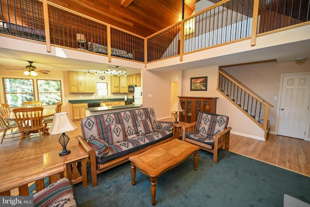 living room featuring ceiling fan, wood-type flooring, a high ceiling, and wooden ceiling