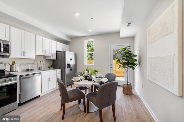 kitchen with stainless steel appliances, light hardwood / wood-style floors, and white cabinets