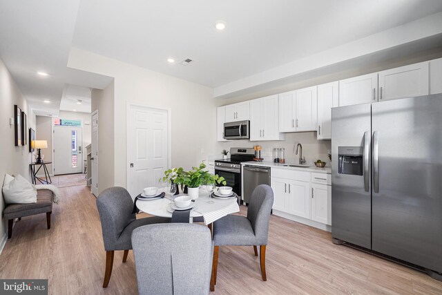 kitchen featuring light wood-type flooring, appliances with stainless steel finishes, sink, and white cabinets