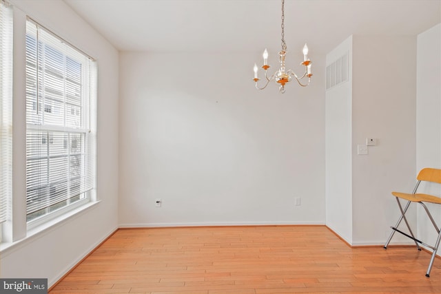 unfurnished room with light hardwood / wood-style flooring and a notable chandelier