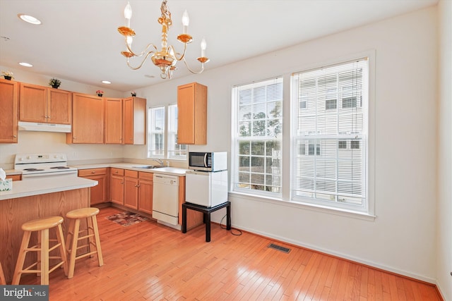 kitchen with a wealth of natural light, white appliances, sink, a notable chandelier, and hanging light fixtures