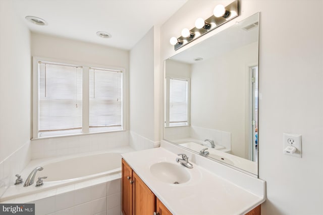 bathroom with vanity and tiled bath