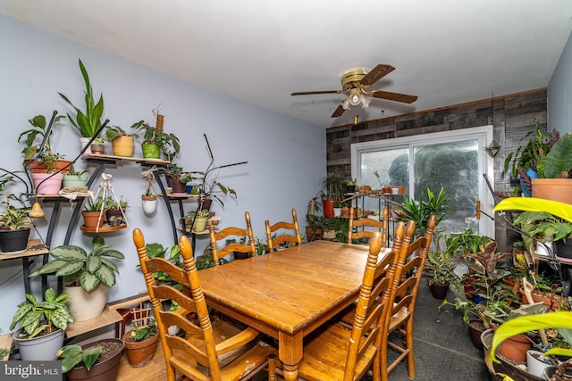 dining room featuring ceiling fan and wood walls