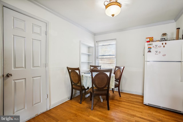 dining area featuring light wood-type flooring and crown molding