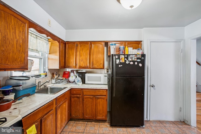 kitchen with black refrigerator, decorative backsplash, and sink