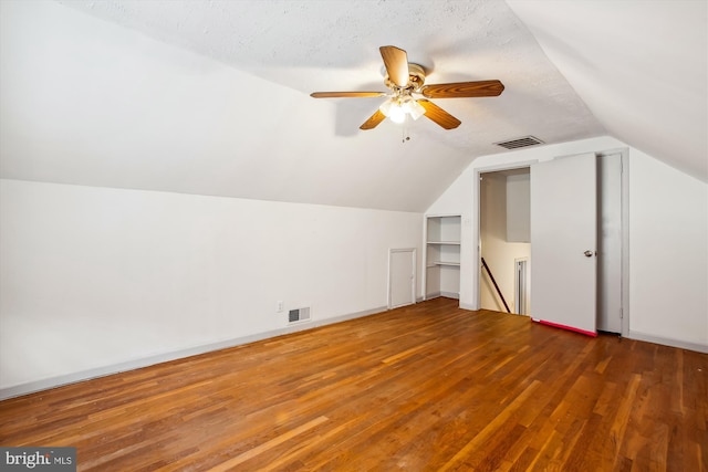 additional living space with vaulted ceiling, ceiling fan, a textured ceiling, and dark hardwood / wood-style floors