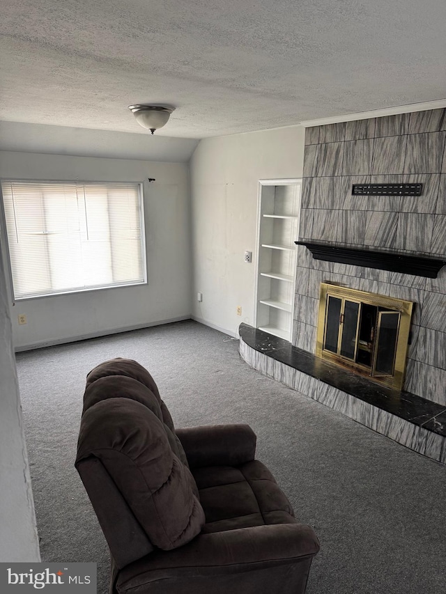 carpeted living room featuring a large fireplace and a textured ceiling