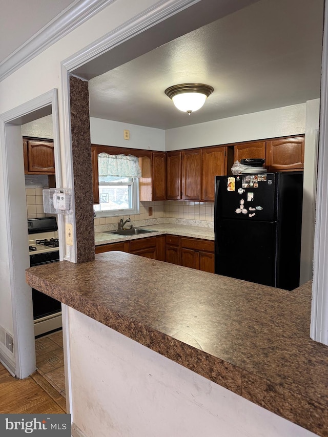 kitchen featuring sink, decorative backsplash, black fridge, and white stove