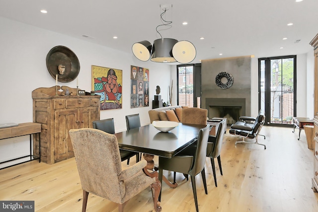 dining room featuring a fireplace, light wood-type flooring, and a wealth of natural light