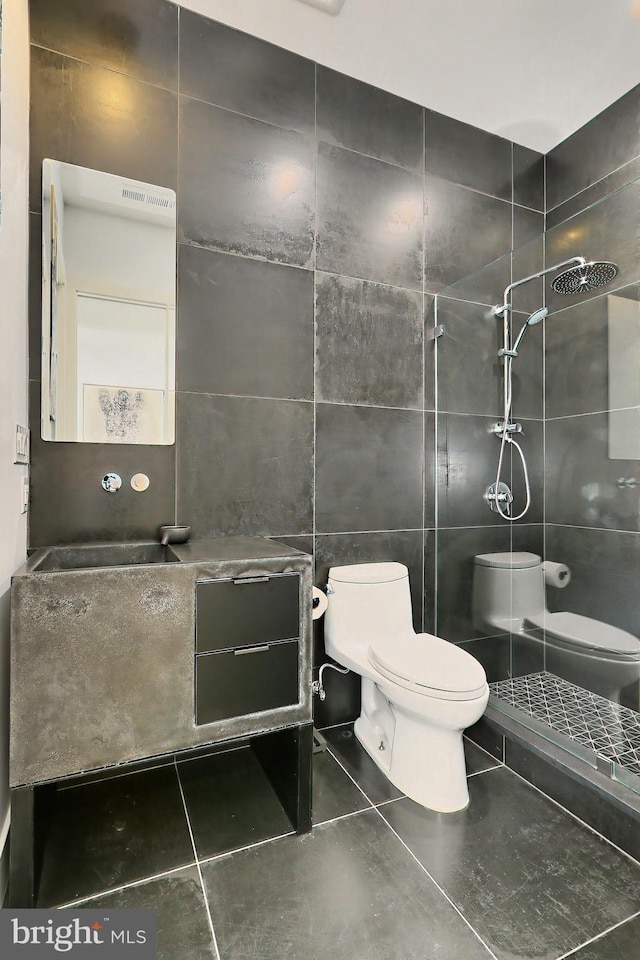 bathroom featuring tile patterned flooring, toilet, tile walls, and walk in shower