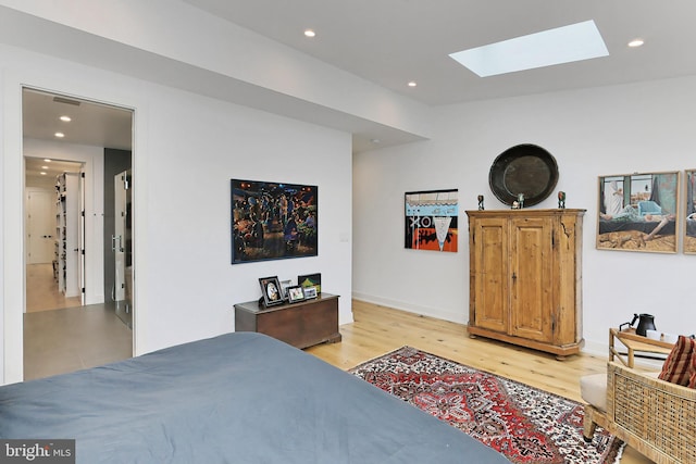 bedroom featuring a skylight and light hardwood / wood-style flooring