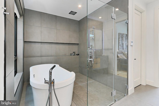 bathroom with tile patterned floors, tile walls, and shower with separate bathtub