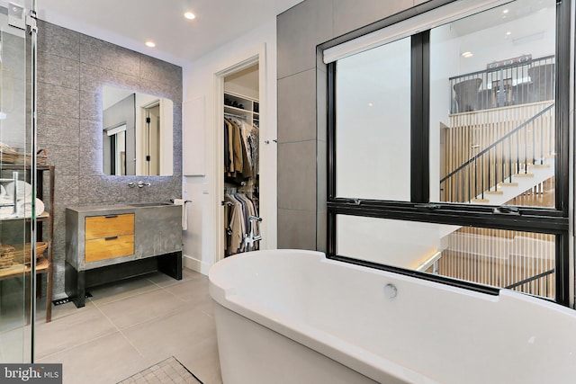 bathroom with tile patterned floors, vanity, tile walls, and a tub