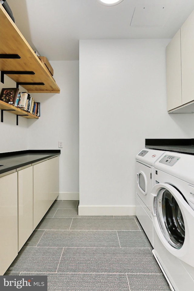 laundry room featuring tile patterned floors, washing machine and dryer, and cabinets