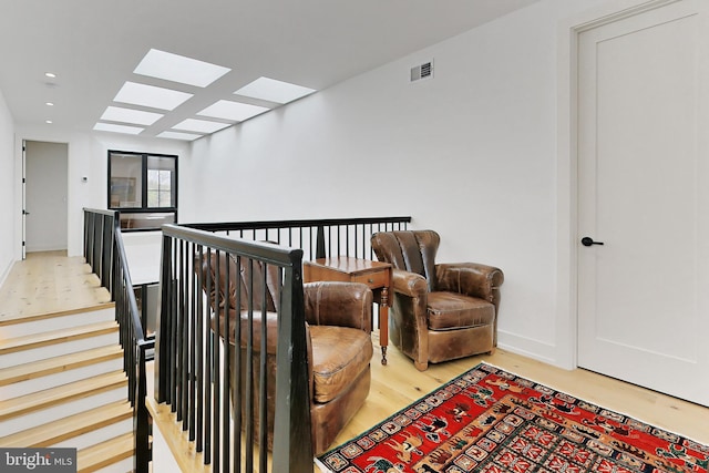 sitting room featuring light wood-type flooring and a skylight