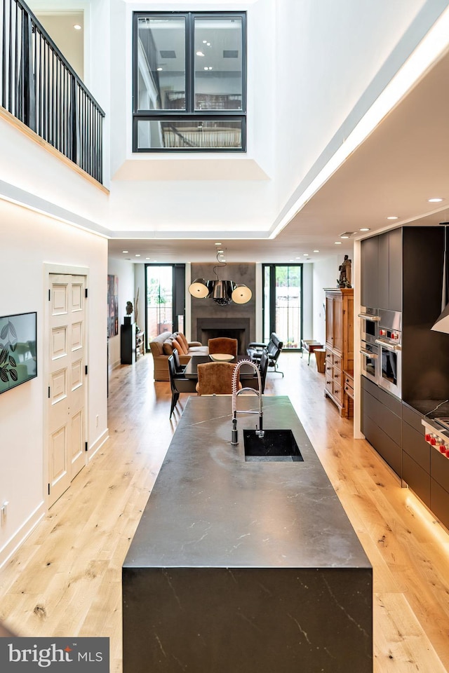 living room with a towering ceiling, sink, a wealth of natural light, and light hardwood / wood-style flooring