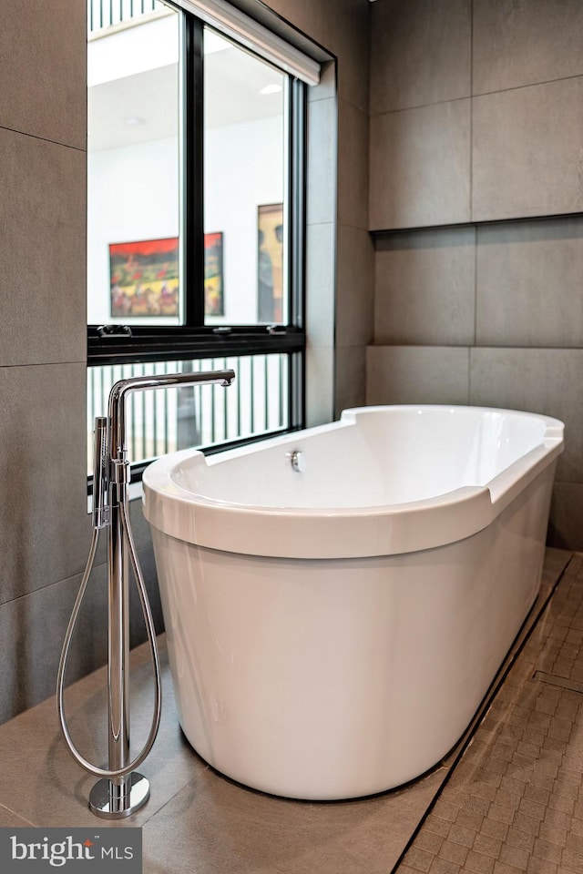 bathroom featuring a bath and tile walls