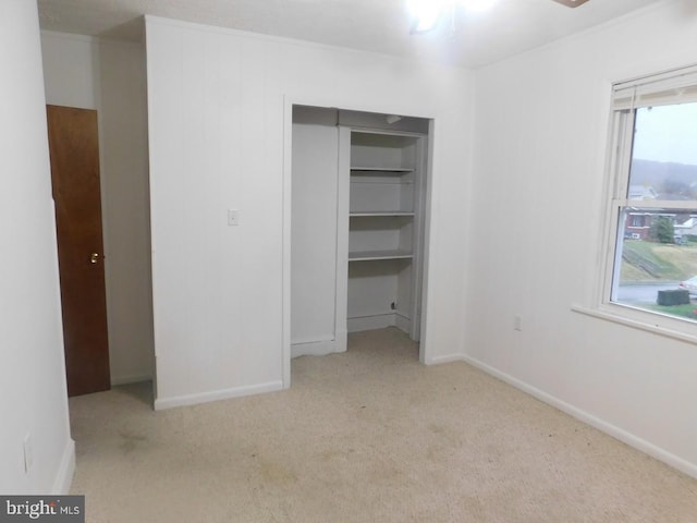 unfurnished bedroom with light colored carpet and a closet