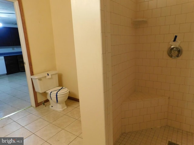 bathroom featuring toilet, tile patterned floors, and a tile shower