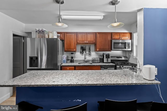 kitchen with stainless steel appliances, light stone counters, sink, light tile patterned flooring, and decorative light fixtures